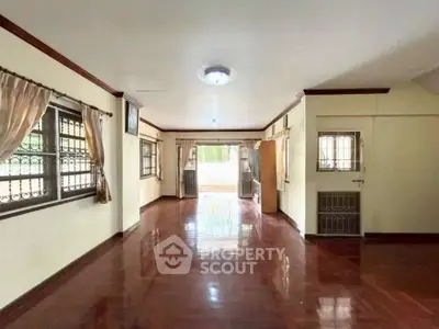 Spacious living room with polished wooden floors and large windows for natural light.