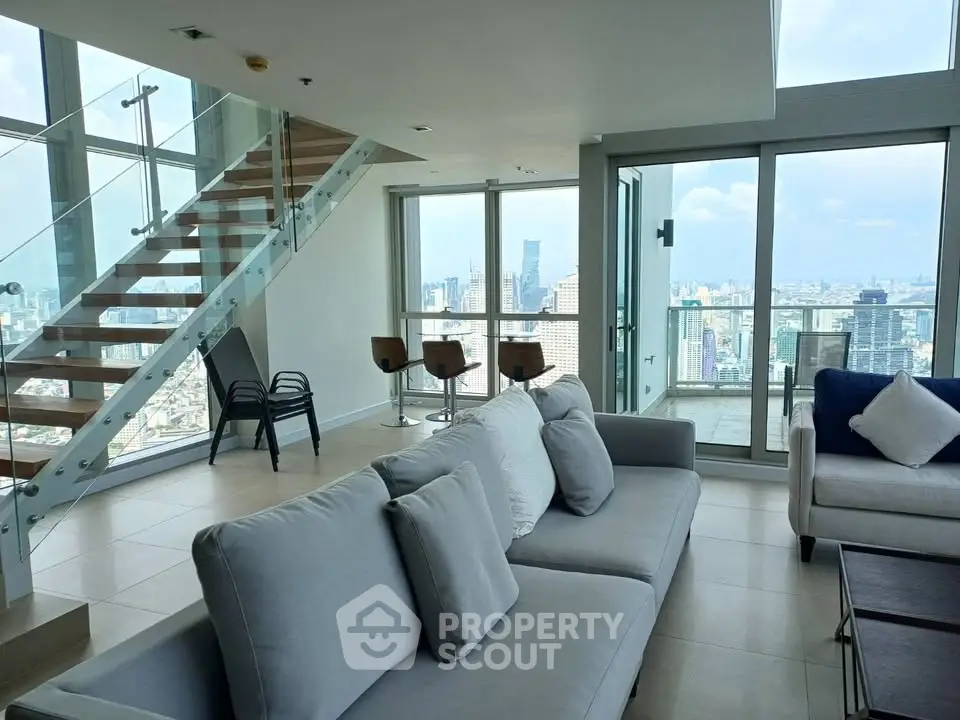 Luxurious modern living room with stunning city view and elegant staircase in high-rise apartment.