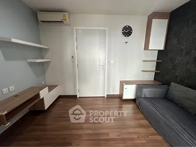 Modern living room with sleek wooden flooring, wall-mounted shelves, and a stylish gray sofa.