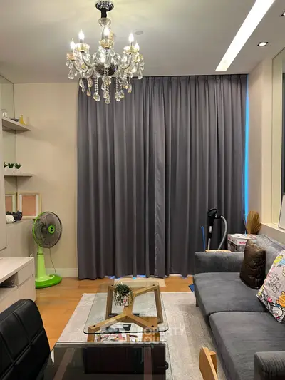 Elegant living room with chandelier and modern decor, featuring a cozy gray sofa and stylish coffee table.