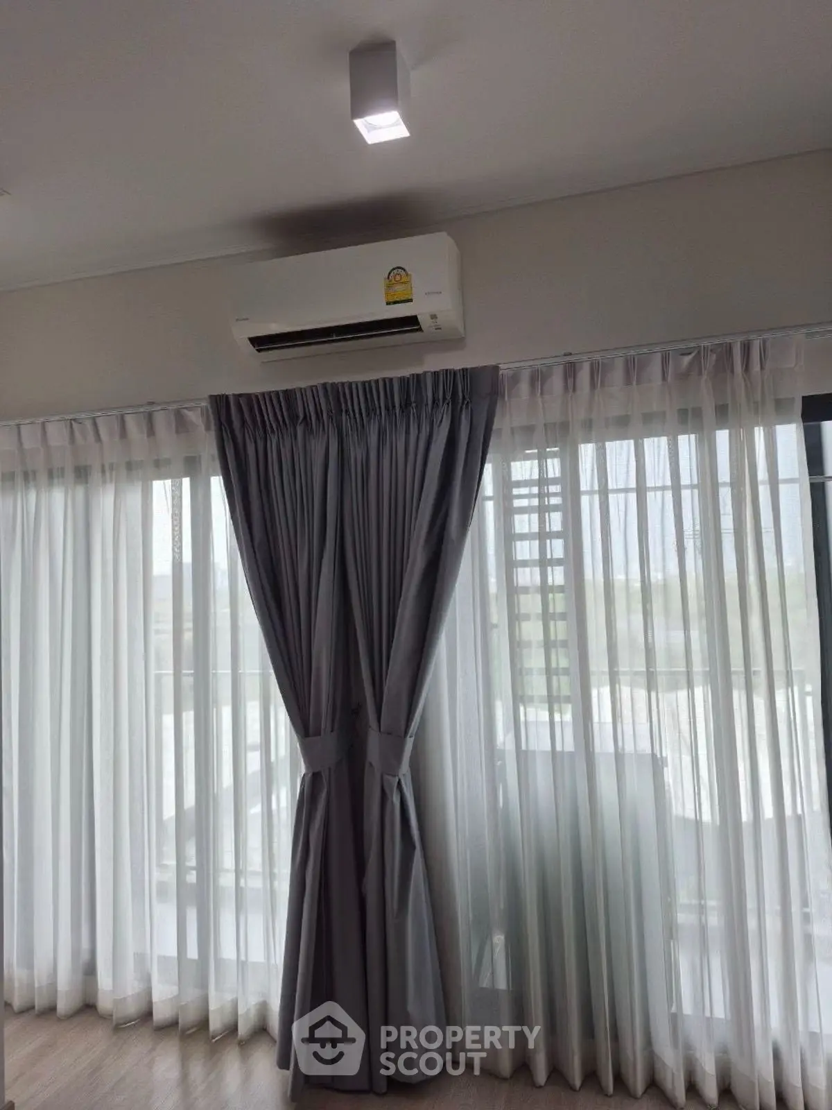 Bright living room with large windows and modern air conditioning unit.