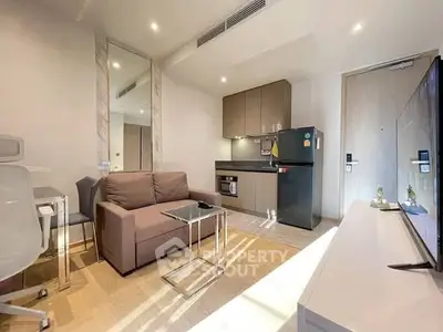 Modern living room with compact kitchen, featuring sleek furniture and natural light.