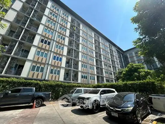 Modern apartment building with parking area under clear blue sky.