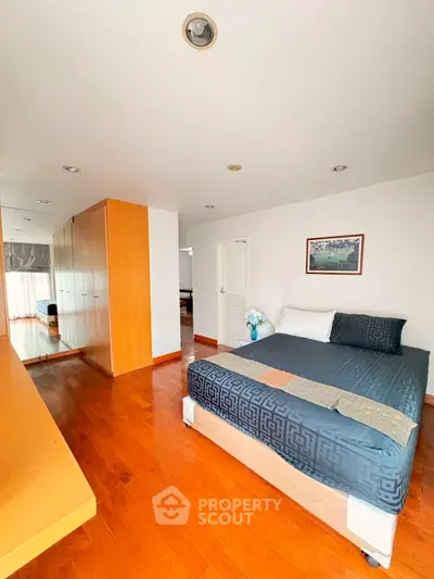 Spacious bedroom with wooden flooring and modern decor in a stylish apartment.