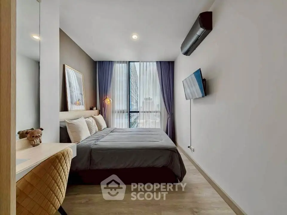 Modern bedroom with stylish decor, large window, and wall-mounted TV in a contemporary apartment.