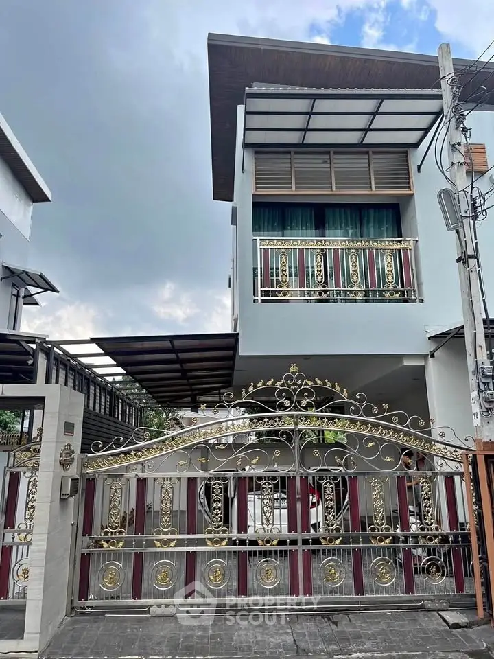 Elegant modern house with ornate gate and balcony, showcasing contemporary architecture and stylish design.
