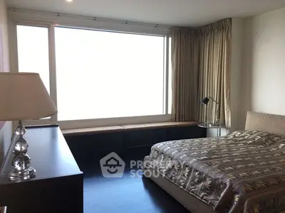 Spacious bedroom with large window and elegant decor in modern apartment.