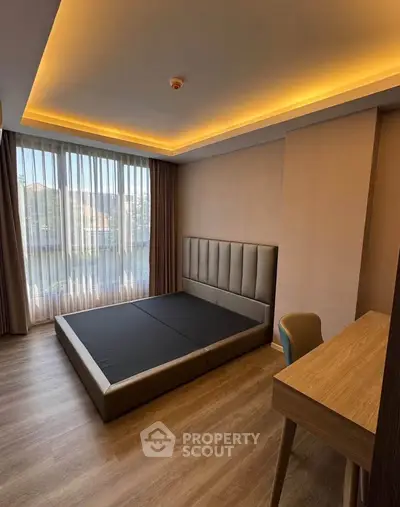 Modern bedroom with sleek design, featuring a large window and stylish furniture, perfect for urban living.