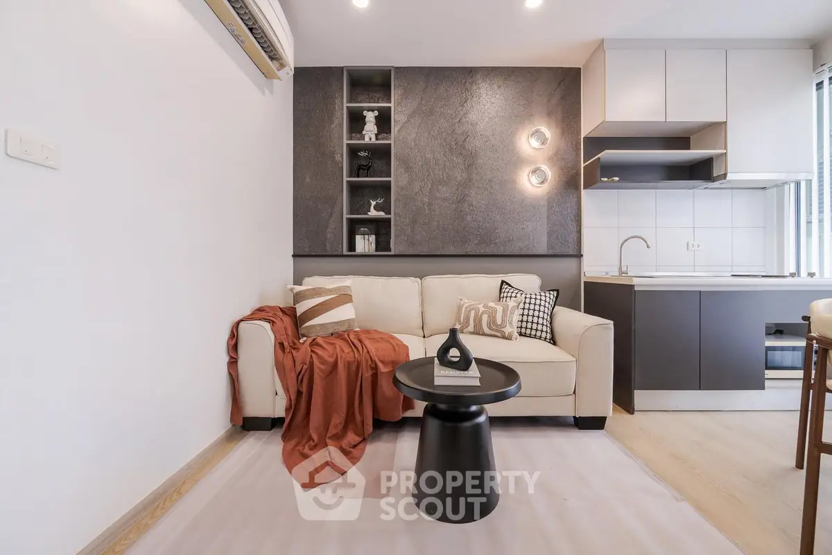 Modern living room with stylish decor and open kitchen layout, featuring cozy sofa and elegant lighting.