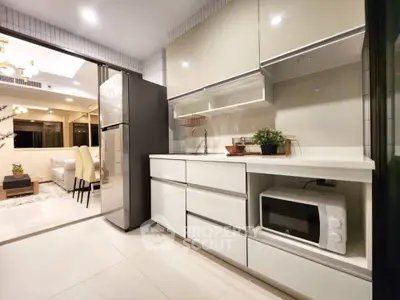 Modern kitchen with sleek cabinetry and open layout leading to a stylish dining area.