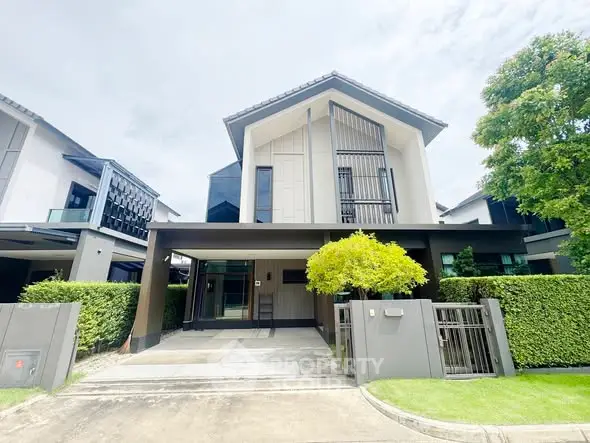 Modern two-story house with sleek design and lush greenery in suburban neighborhood.