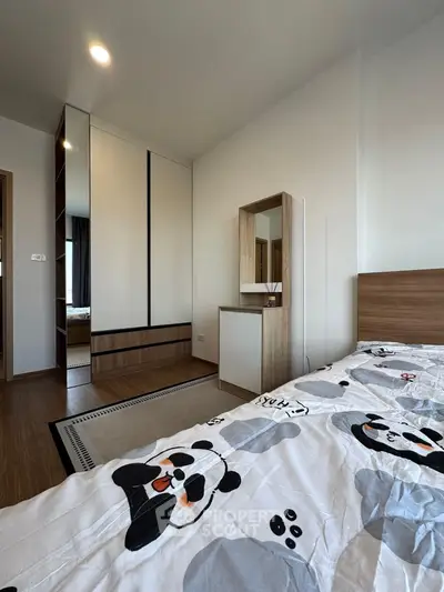 Modern bedroom with stylish decor and panda-themed bedding, featuring a sleek wardrobe and wooden flooring.