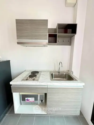 Modern compact kitchen with sleek cabinetry and electric stove, perfect for urban living.