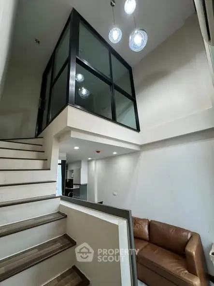 Modern duplex interior with stylish staircase and glass-walled upper room