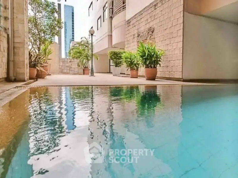 Luxurious apartment pool area with modern architecture and lush greenery.