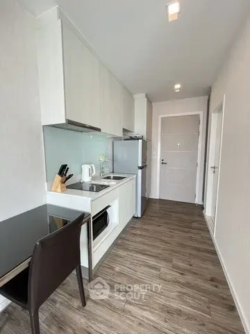 Modern kitchen with sleek appliances and wooden flooring in a compact layout.
