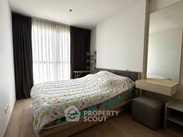 Cozy bedroom with modern decor and ample natural light from large window.