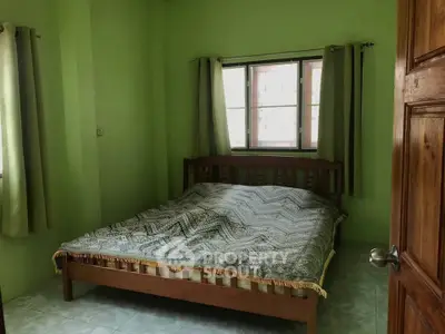 Cozy bedroom with wooden bed frame and green walls, perfect for relaxation.