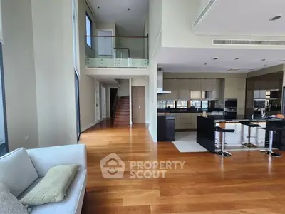 Luxurious open-plan living room with high ceilings and modern kitchen in upscale apartment.