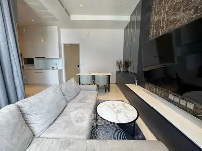Modern living room with sleek design, marble accents, and open kitchen layout.