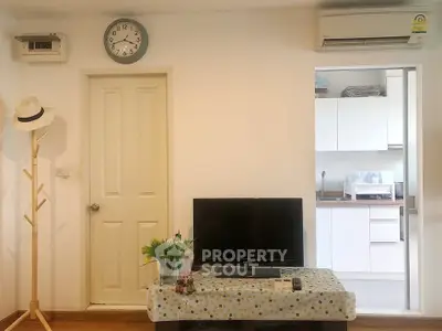 Cozy living room with TV, air conditioning, and kitchen view