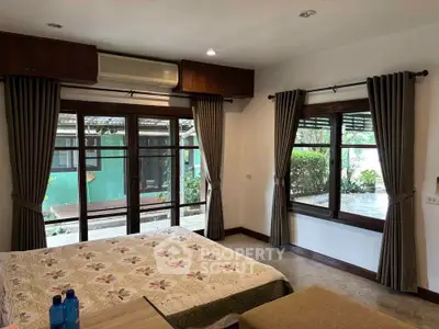 Cozy bedroom with large windows and garden view, featuring elegant curtains and a comfortable bed.
