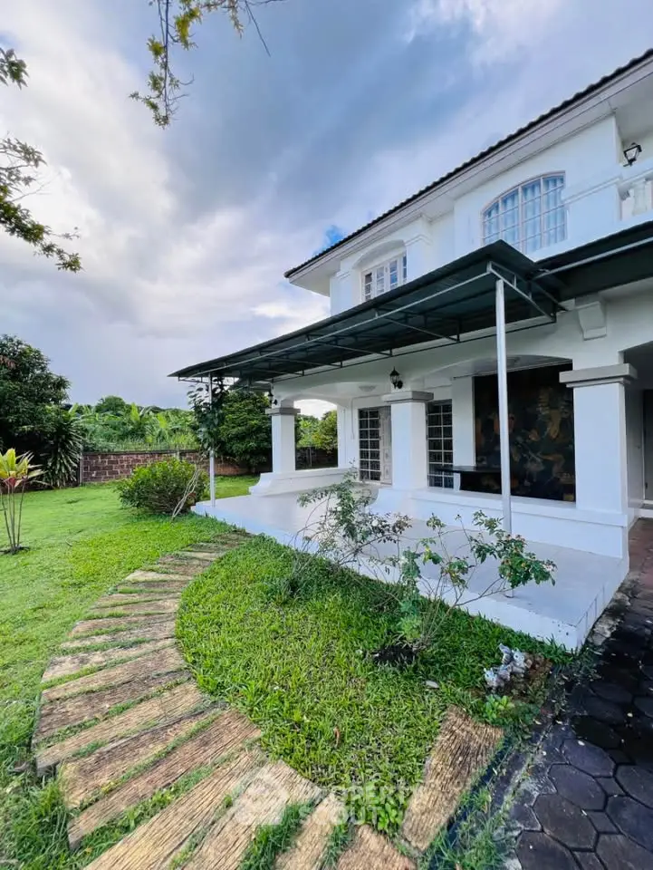 Charming two-story house with lush garden and spacious patio, perfect for outdoor relaxation and entertaining.