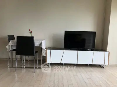 Modern living room with sleek TV stand and dining area, featuring minimalist decor and wooden flooring.