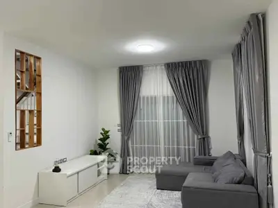 Modern living room with gray sofa, elegant curtains, and minimalist decor