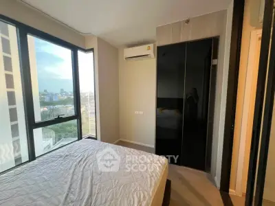 Modern bedroom with large windows and city view, featuring sleek wardrobe and air conditioning.