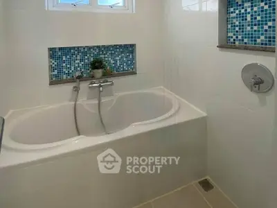 Modern bathroom with stylish bathtub and mosaic tile accents