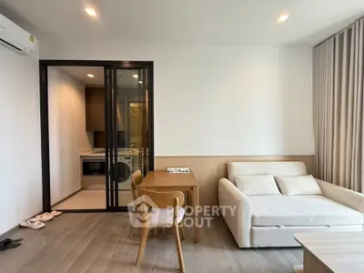 Modern living room with cozy sofa and dining area, featuring a sleek open kitchen design.