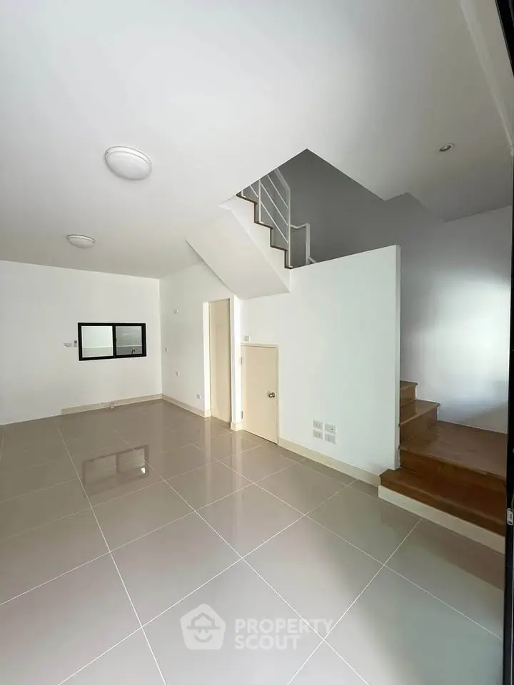 Spacious modern interior with sleek staircase and tiled flooring, perfect for contemporary living.
