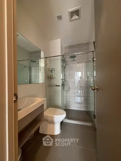Modern bathroom with glass shower and sleek fixtures in contemporary apartment.