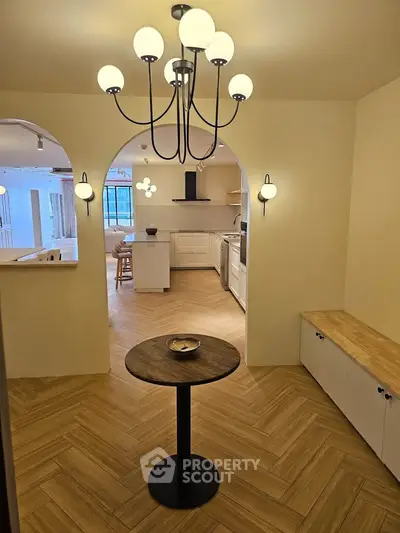 Elegant open-layout kitchen with modern lighting and wooden flooring, perfect for stylish living.