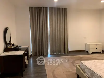 Spacious bedroom with elegant decor and large windows for natural light.
