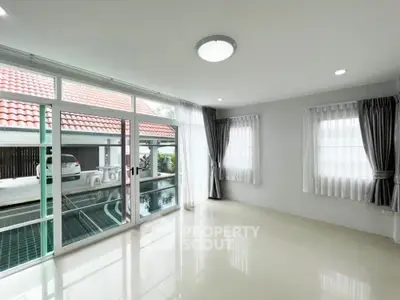 Spacious living room with pool view and large windows in modern home