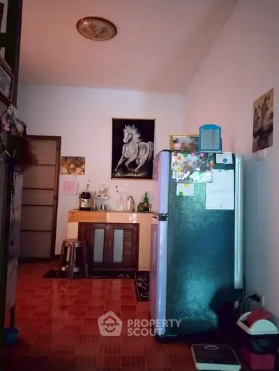 Cozy kitchen with fridge and artwork, featuring warm lighting and tiled flooring.