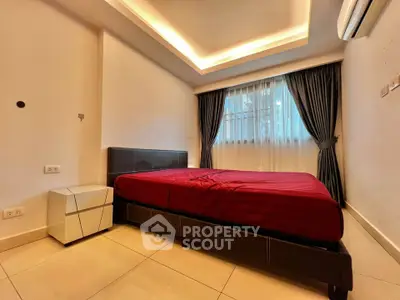 Modern bedroom with stylish lighting and red bedding in a contemporary apartment.