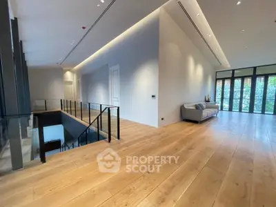 Spacious modern living area with wooden flooring and large windows.