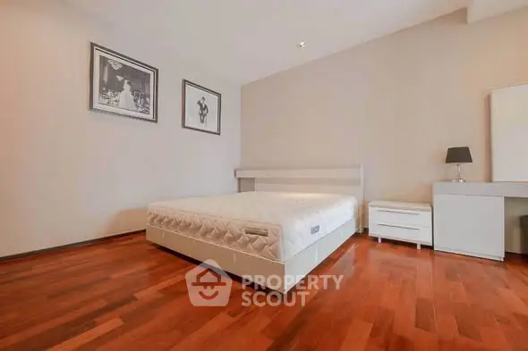 Spacious bedroom with wooden flooring and modern decor in a stylish apartment.
