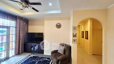 Spacious living room with modern decor and large window, featuring a comfortable armchair and stylish rug.
