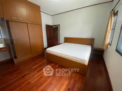 Spacious bedroom with wooden flooring and built-in wardrobe in modern apartment.