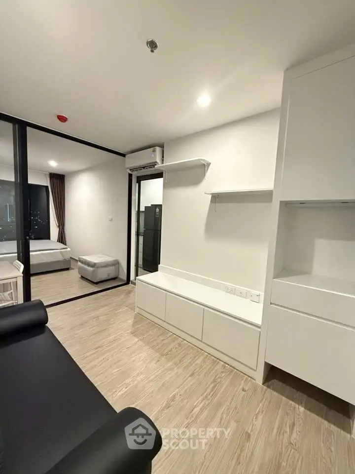 Modern apartment interior with sleek design, featuring a cozy living area and bedroom with glass partition.