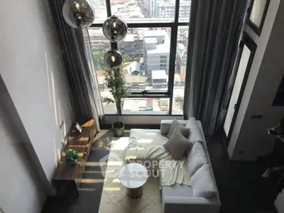Modern living room with large windows and city view, featuring stylish furniture and decor.