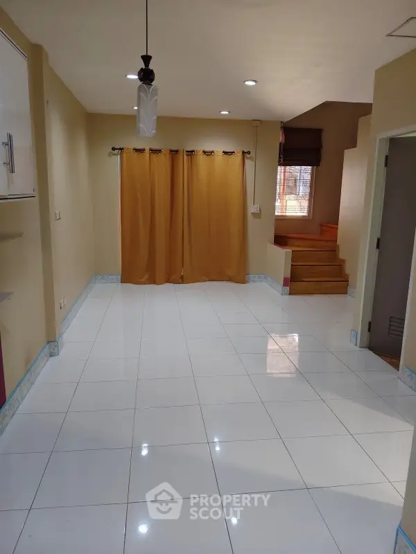Spacious living room with tiled flooring and staircase, ideal for modern family living.