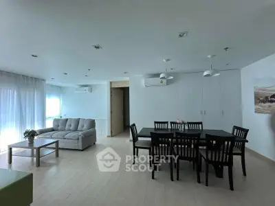 Spacious modern living room with dining area, featuring sleek furniture and ample natural light.