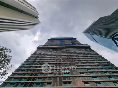 Stunning skyscraper view with modern architectural design against a cloudy sky, showcasing urban living at its finest.