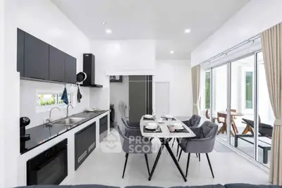 Modern open-layout kitchen and dining area with sleek black cabinets and large windows.