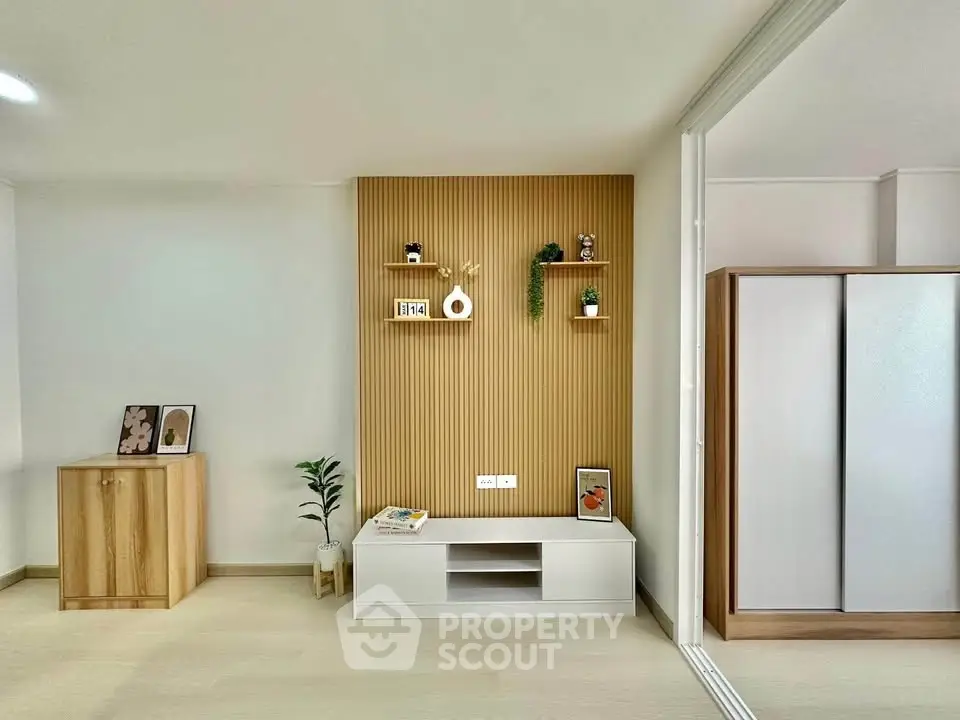 Modern living room with stylish wooden paneling and sleek storage solutions.